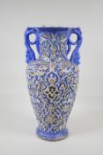 A Persian blue ground pottery two handled vase, with iznik style raised polychrome scrolling