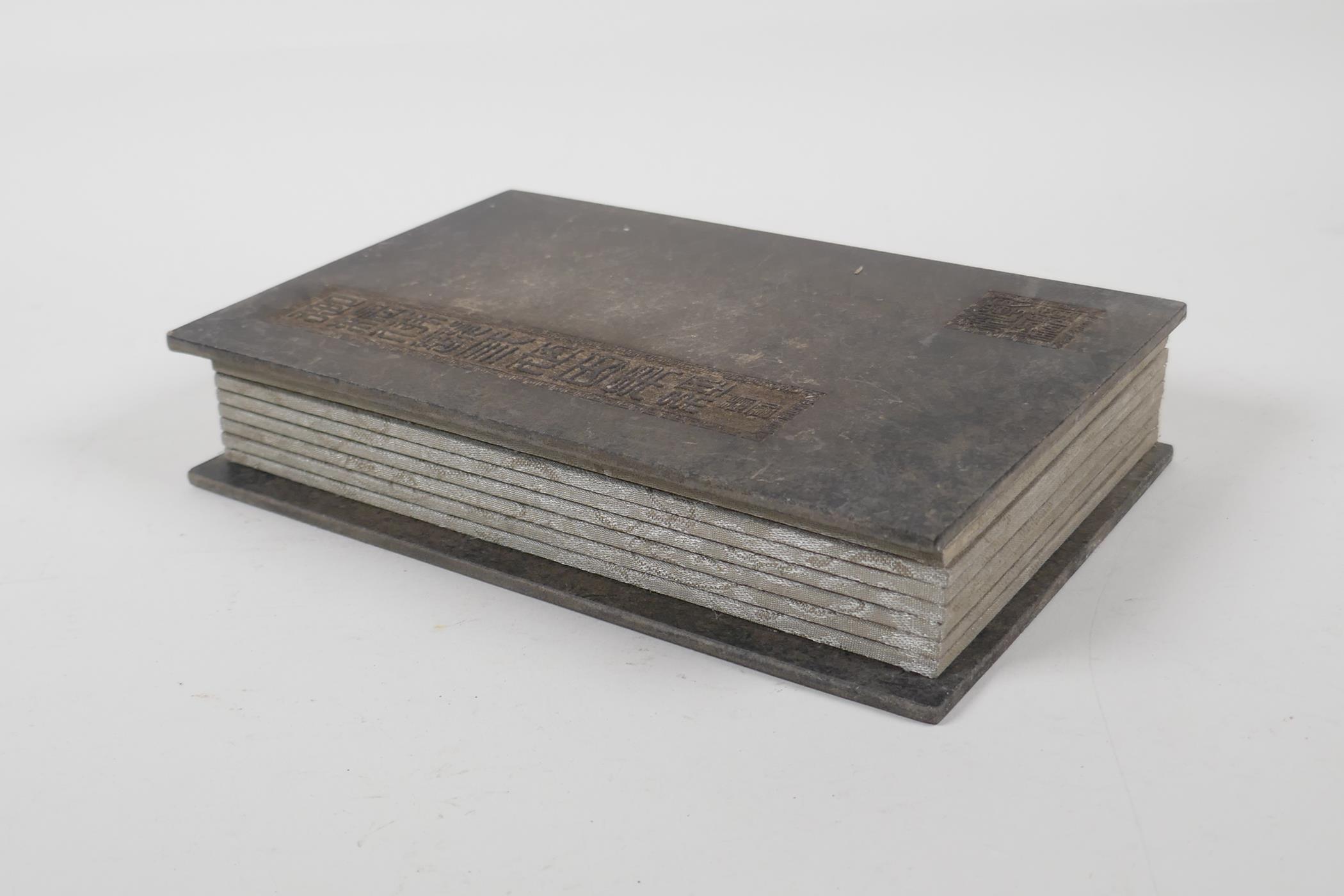 A Chinese silk and wood bound book containing black hardstone tablets with engraved and gilt