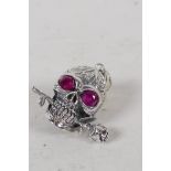 A sterling silver skull pendant, with red stone eyes 1" long