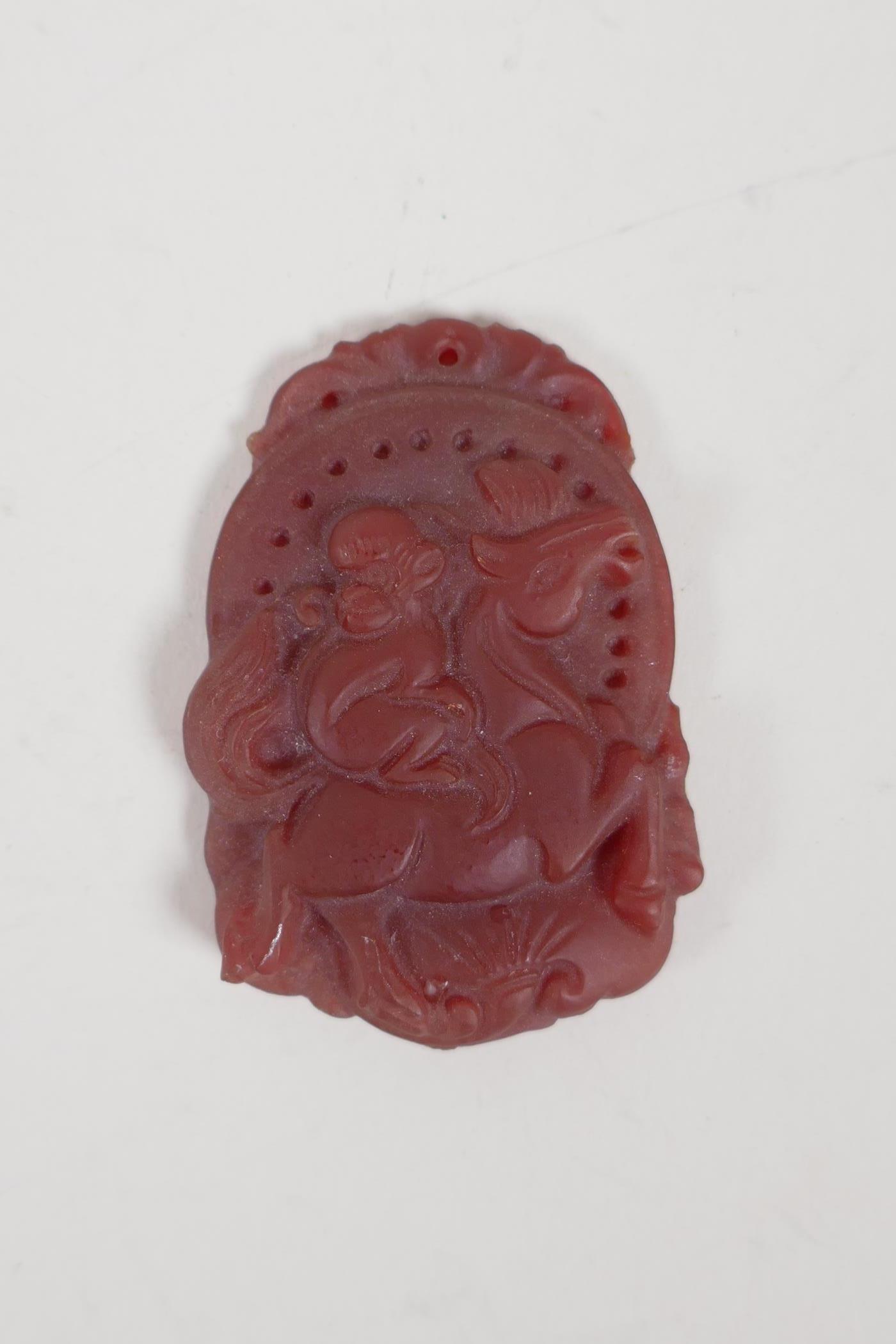 A Chinese agate amulet with carved decoration of a monkey riding a pony. 1½" x 2"