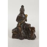A Chinese filled bronze figure of Quan Yin seated on an elephant and carrying a gilt lotus flower,