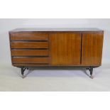 A mid-century mahogany sideboard with ebonised detail, comprising two cupboards and four drawers,
