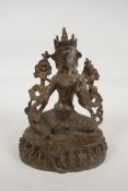 A Sino Tibetan gilt bronze of a female deity seated on a lotus throne, 7" high
