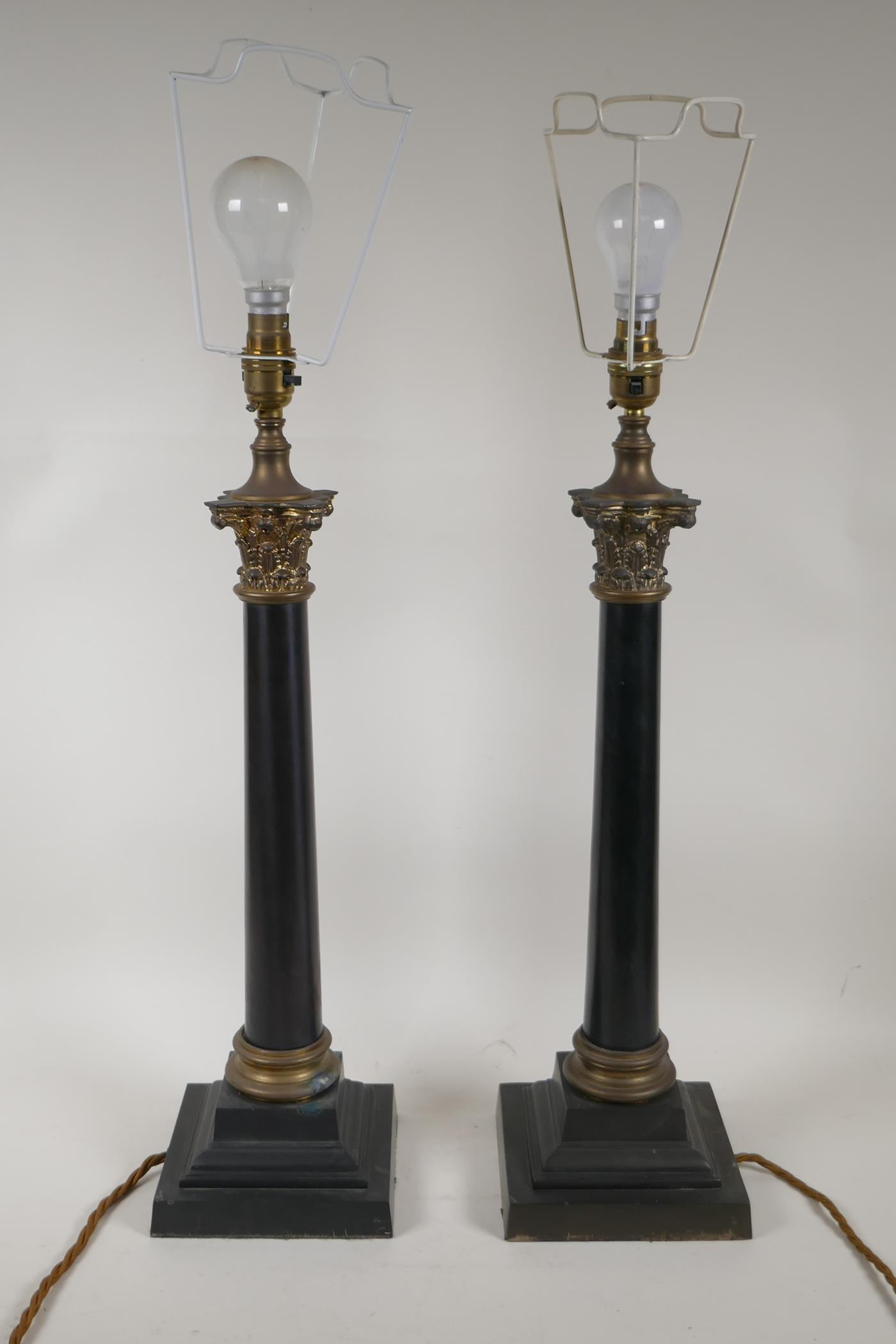 A pair of ebonised metal and ormolu Corinthian column table lamps, 22" high