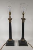 A pair of ebonised metal and ormolu Corinthian column table lamps, 22" high