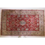 A vintage Persian silk rug with floral designs and central medallion on a red field with blue and