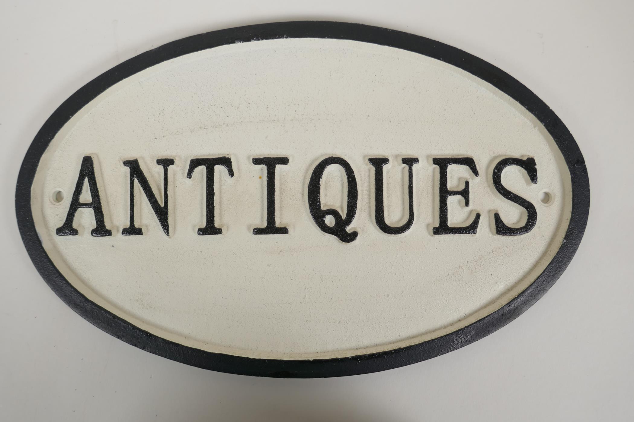 A cast iron Antiques sign, 13" x 9"