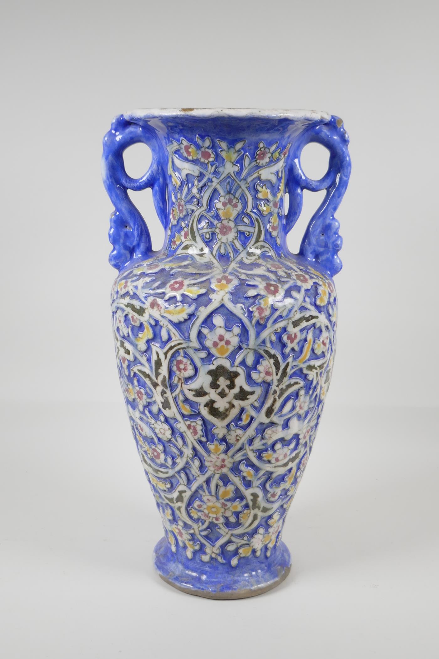 A Persian blue ground pottery two handled vase, with Iznik style raised polychrome scrolling