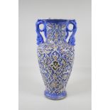 A Persian blue ground pottery two handled vase, with Iznik style raised polychrome scrolling