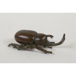 A Japanese bronze okimono in the form of a horned beetle, impressed mark to base, 3" long