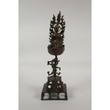 A Nepalese/Tibetan bronze figure of Buddha seated on a lotus flower raised on a dragon form stem,