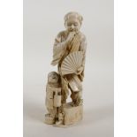 A Japanese Meiji period ivory okimono figure of a gentleman holding a fan with a child, signed to