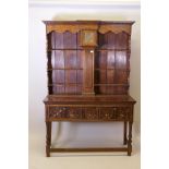 An early C20th oak Jacobean style dresser, the rack fitted with a fusee clock with brass dial, and