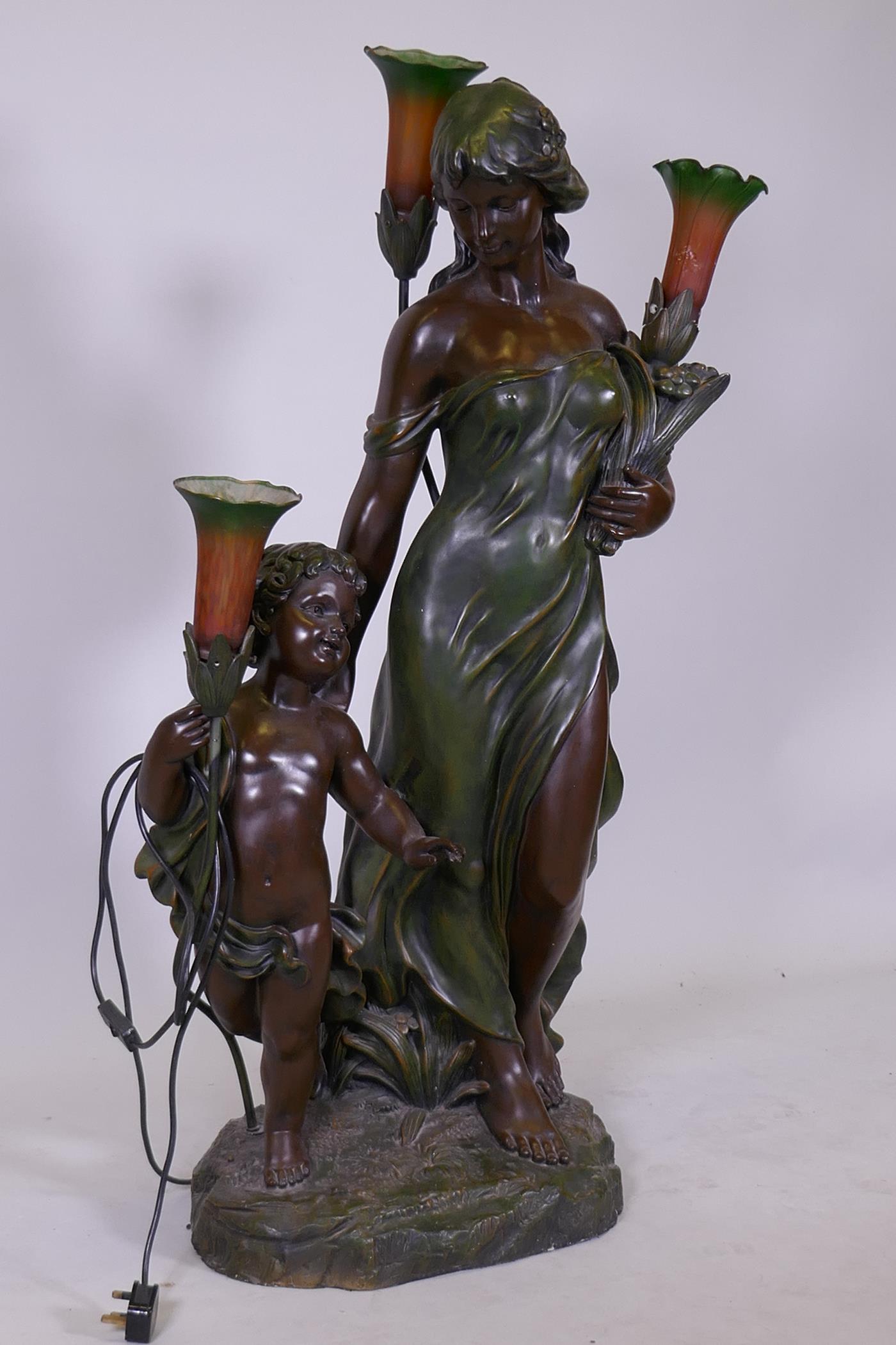 An Art Nouveau style bronzed composition three branch floor lamp in the form of maiden with child,