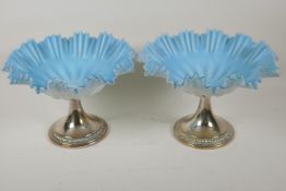 A pair of blue over white milk glass fruit bowls of frilled design on silver plated pedestal