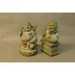 A concrete garden figure of a smiling Buddha and another of a temple dog, 20" high