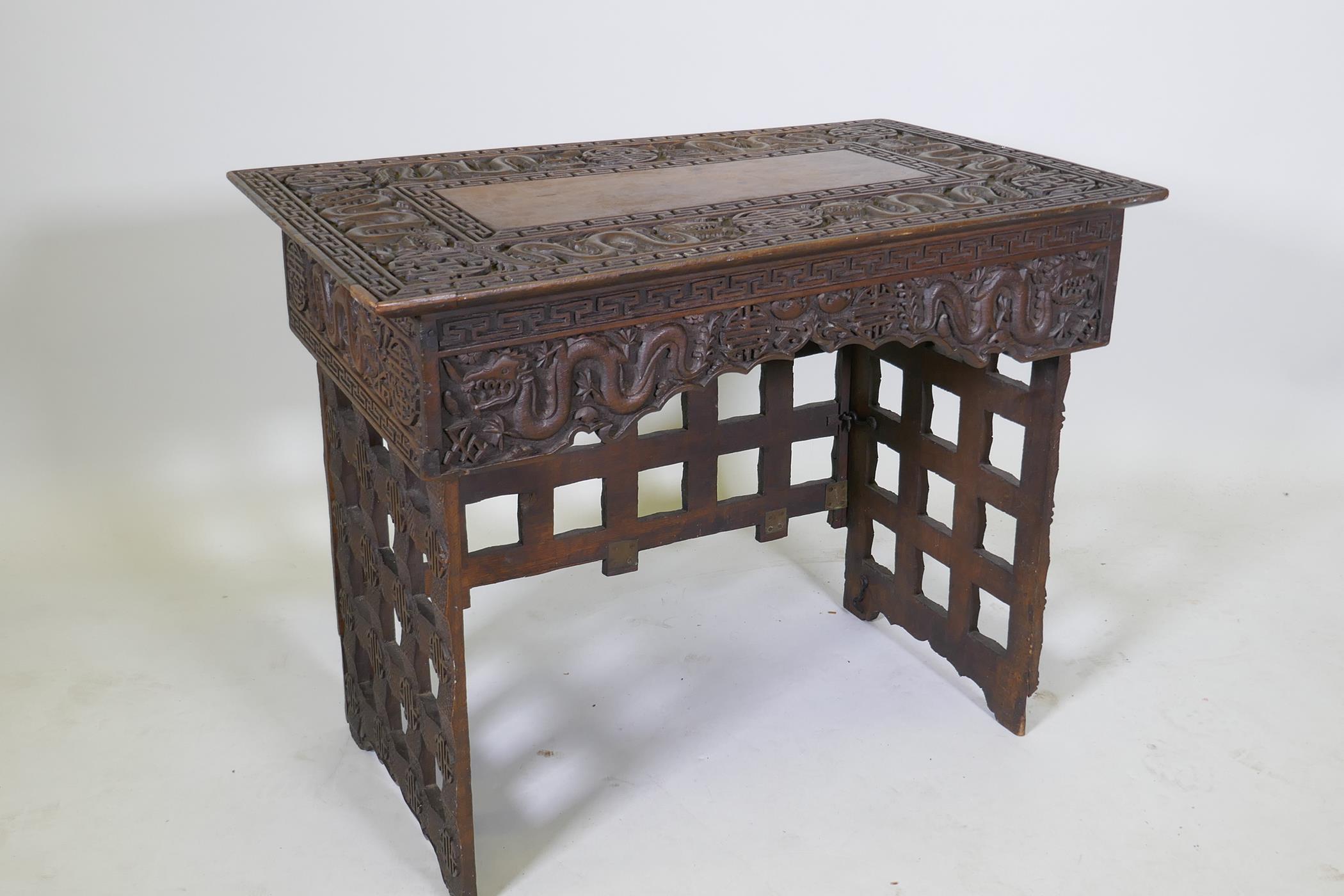 A C19th Chinese carved hardwood travel desk with a pierced folding base, decorated with dragons - Image 6 of 7