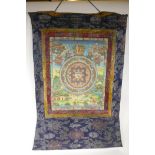 A Tibetan tangka, hand painted with gilt details, in an embroidered silk surround, 25½" x 33"