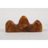 A Chinese amber soapstone brush rest/seal, with carved gourd decoration, 3" long