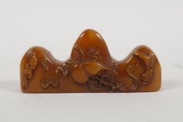 A Chinese amber soapstone brush rest/seal, with carved gourd decoration, 3" long