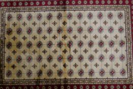An ivory ground full pile Kashmir rug with Bokhara design and red border, 49" x 75"