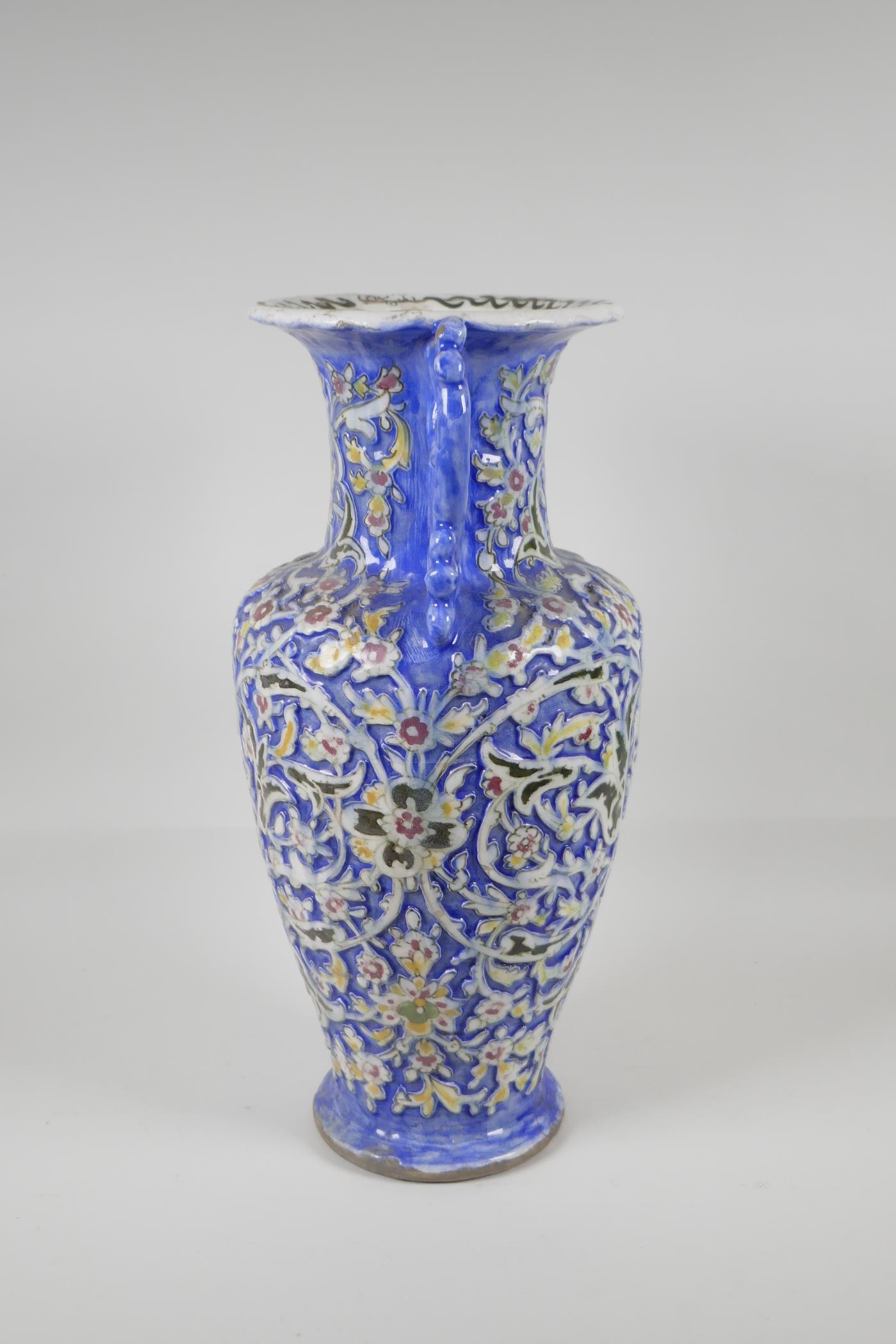 A Persian blue ground pottery two handled vase, with Iznik style raised polychrome scrolling - Image 2 of 7