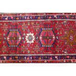 A fine woven red ground Persian Heriz full pile runner with a geometric medallion design, 32" x 128"