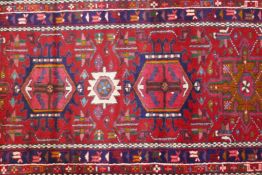 A fine woven red ground Persian Heriz full pile runner with a geometric medallion design, 32" x 128"