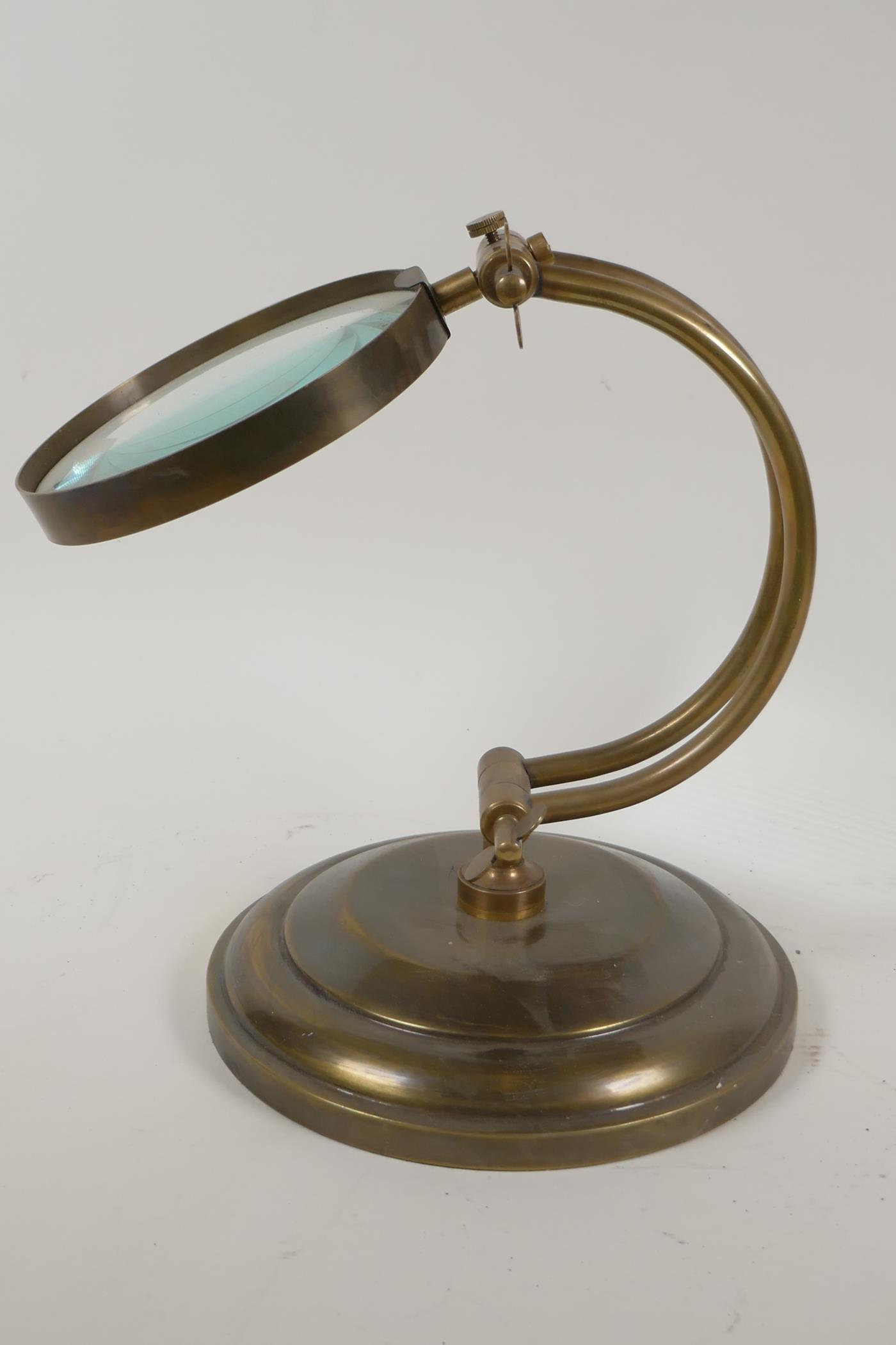 An industrial style brass framed desk top magnifying glass, lens 5" diameter