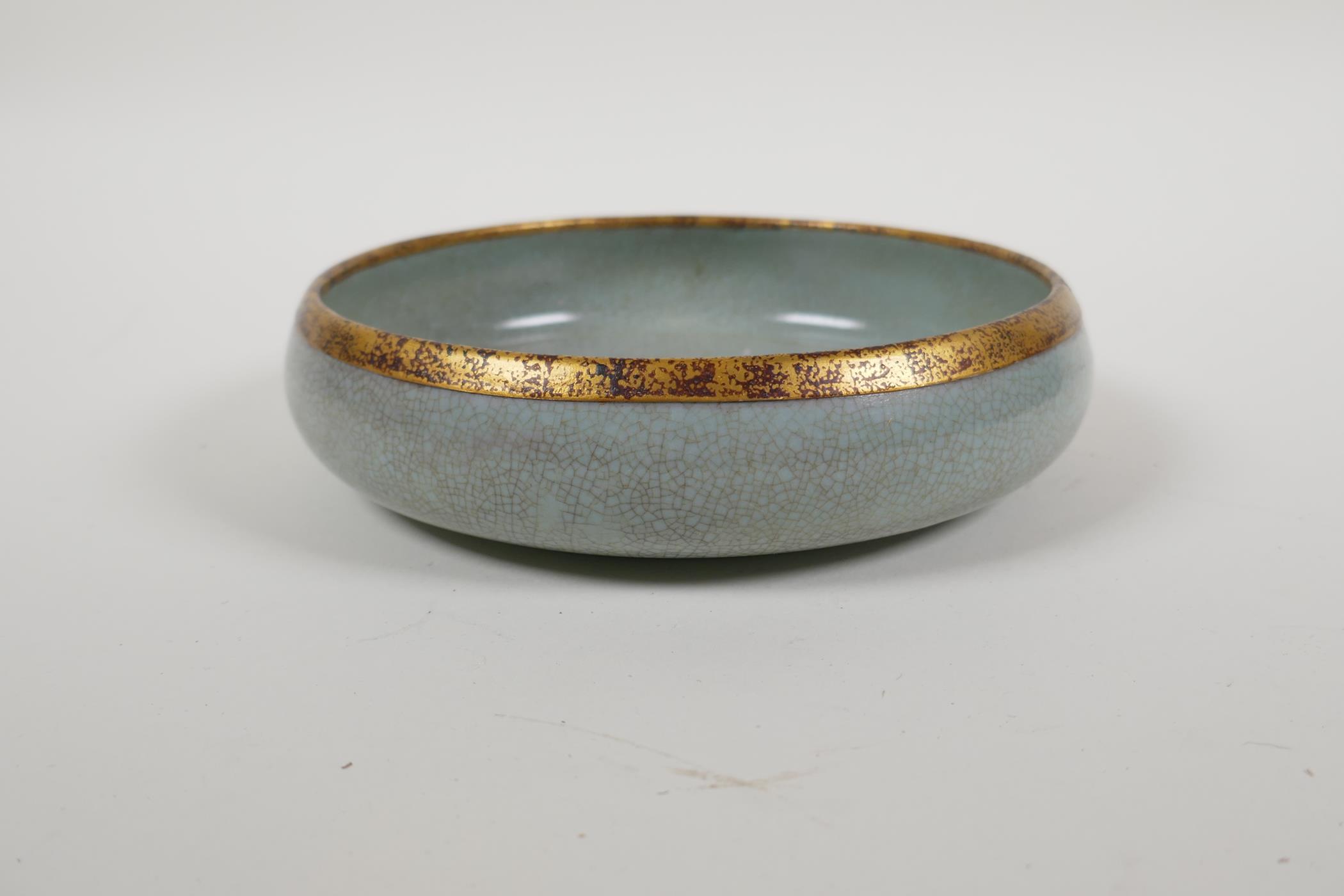 A celadon crackle glazed Ru ware style porcelain dish with a gilt metal rim, the base with