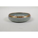 A celadon crackle glazed Ru ware style porcelain dish with a gilt metal rim, the base with