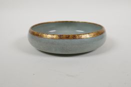 A celadon crackle glazed Ru ware style porcelain dish with a gilt metal rim, the base with