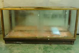 A vintage brass and mahogany shop display cabinet with mirrored back and sliding glass front