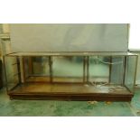 A vintage brass and mahogany shop display cabinet with mirrored back, bears maker's label Harris &