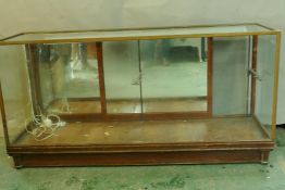 A vintage brass and mahogany shop display cabinet with mirrored back, bears label Harris and Sheldon