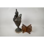 A bronzed spelter classical urn with Baccus mask handles and embossed swag decoration on a marble