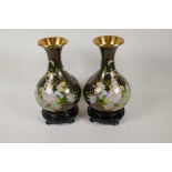 A pair of Chinese bulbous cloisonne vases decorated with flowers, on hardwood stands, 12½" high