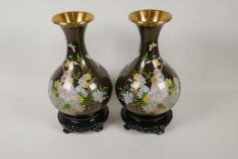 A pair of Chinese bulbous cloisonne vases decorated with flowers, on hardwood stands, 12½" high