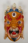 A Tibetan carved and painted wood mask of a three eyed wrathful deity, 8" x 13"