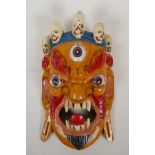 A Tibetan carved and painted wood mask of a three eyed wrathful deity, 8" x 13"