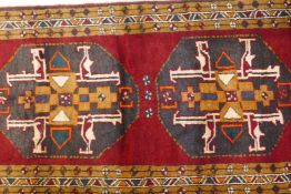 A full pile hand woven Persian runner with a black medallion design on a rich red field, 150" x 41"