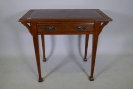 An Arts and Crafts oak desk with single drawer and inset leather top, raised on square tapering