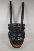 An African carved and painted wood tribal mask, 12" wide, 31" high