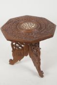 A miniature Indian table with carved and bone inlaid decoration on a folding base, 9" high