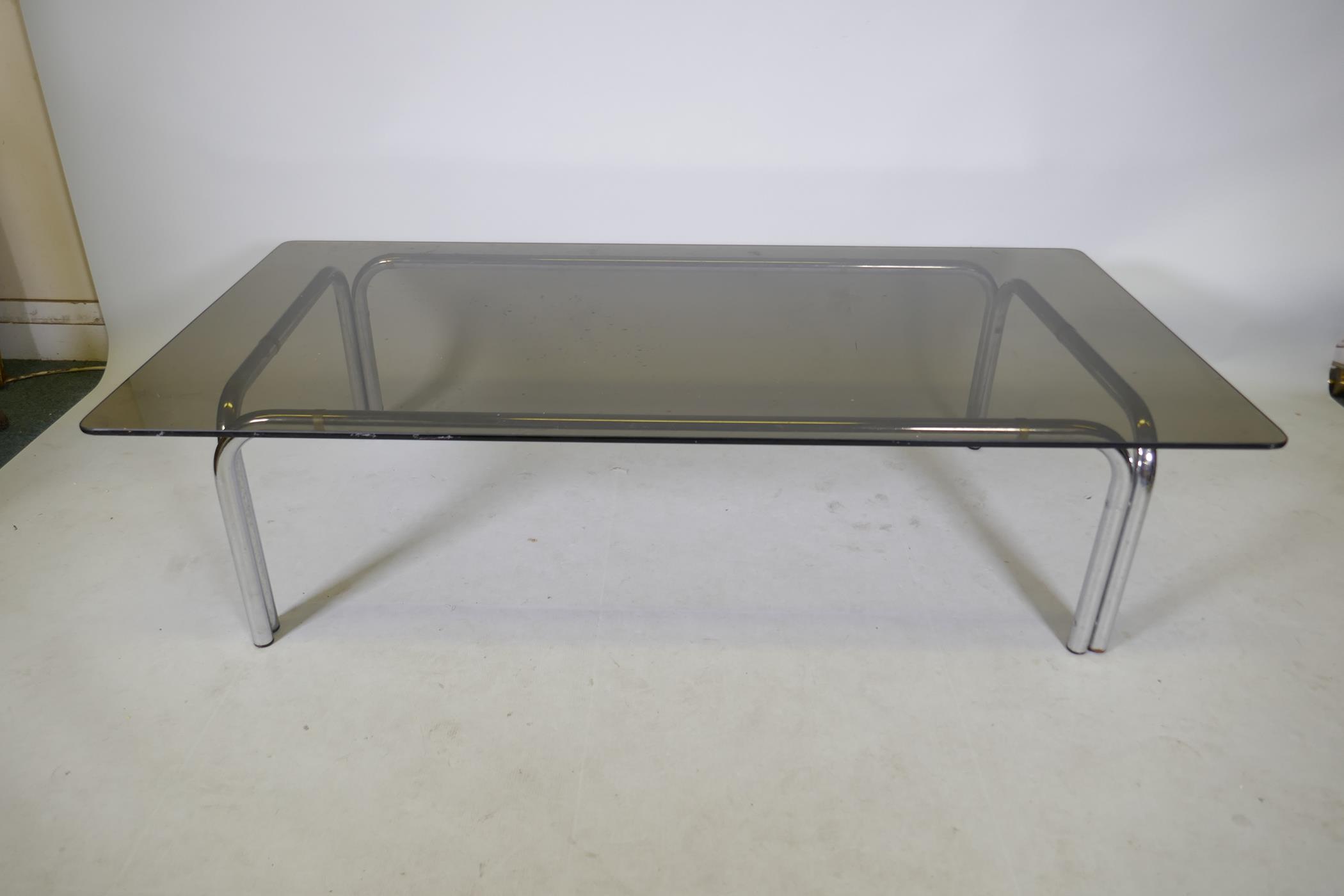 A chromed metal and smoked glass contemporary coffee table, 59" x 29", 15" high