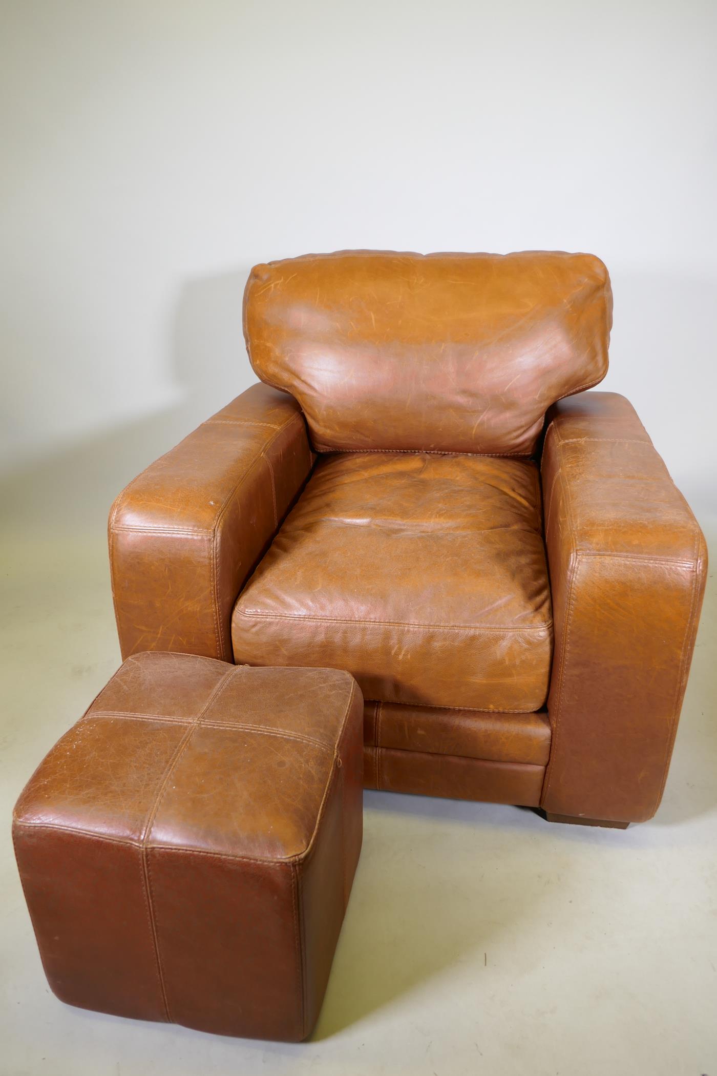 A contemporary leather armchair and matching pouffe, 40" x 40" x 36" high