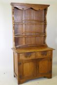 A Cotswold School style Arts & Crafts oak cottage dresser of small proportions, the rack with shaped