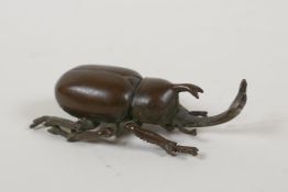 A Japanese bronze okimono in the form of a horned beetle, impressed mark to base, 3" long