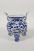 A blue and white porcelain two handled censer raised on tripod supports with dragon decoration,