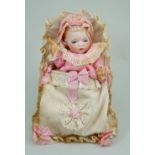 A reproduction bisque head baby in papoose,